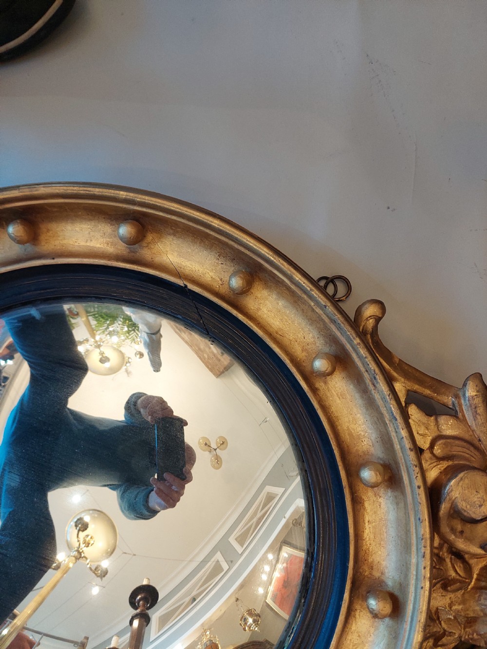 A circular Regency giltwood convex wall mirror featuring a carved eagle surmount, spherical balls around the moulded frame, a black reeded slip, and an acanthus leaf apron. View IV