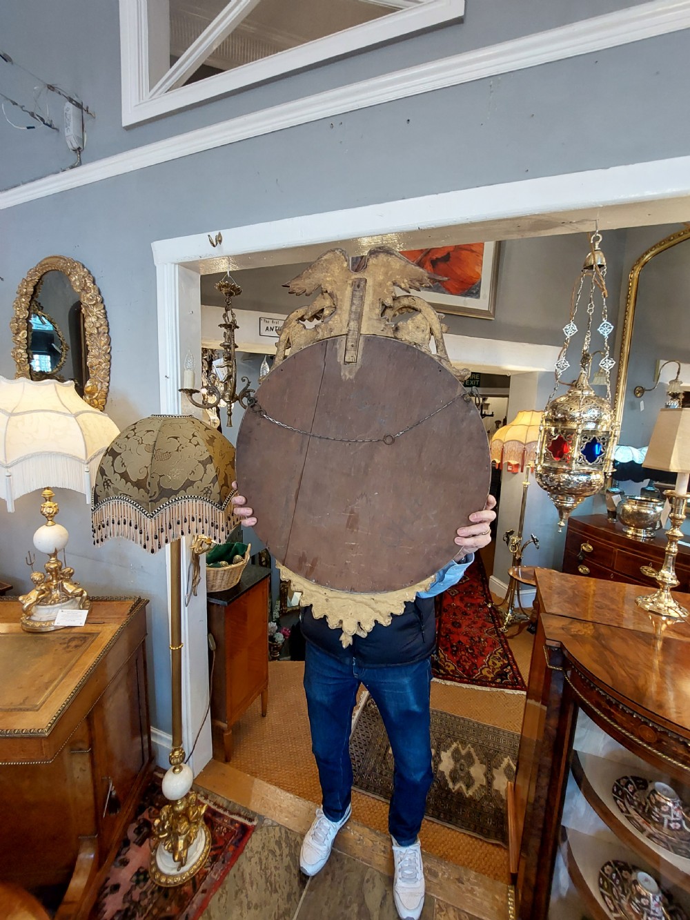 A circular Regency giltwood convex wall mirror featuring a carved eagle surmount, spherical balls around the moulded frame, a black reeded slip, and an acanthus leaf apron. View VII