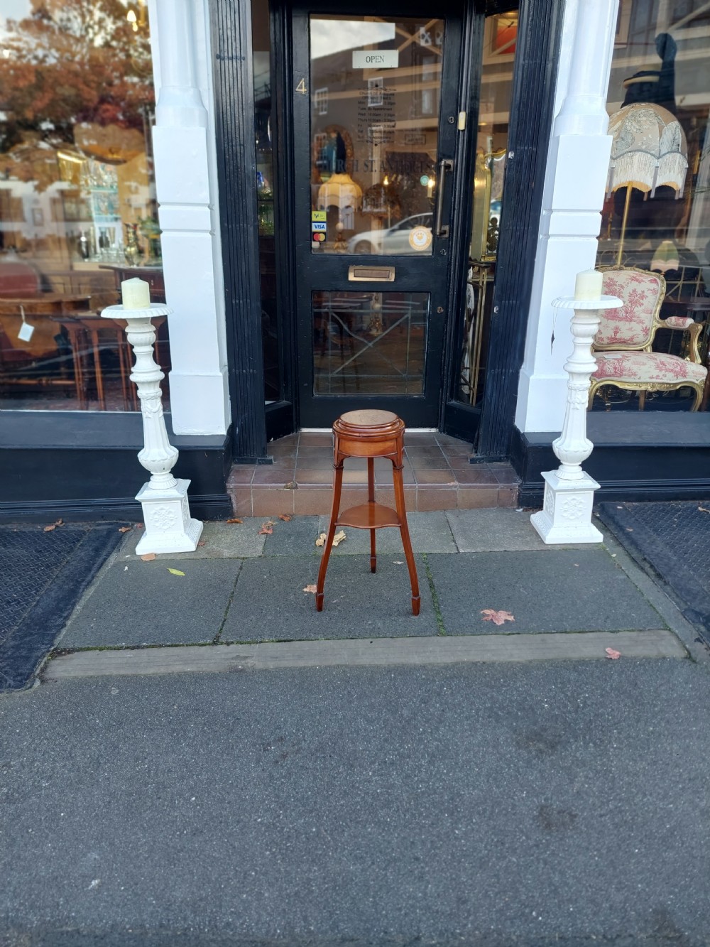An Edwardian circular walnut vase stand with slender splayed legs and a lower triangular tier. View II