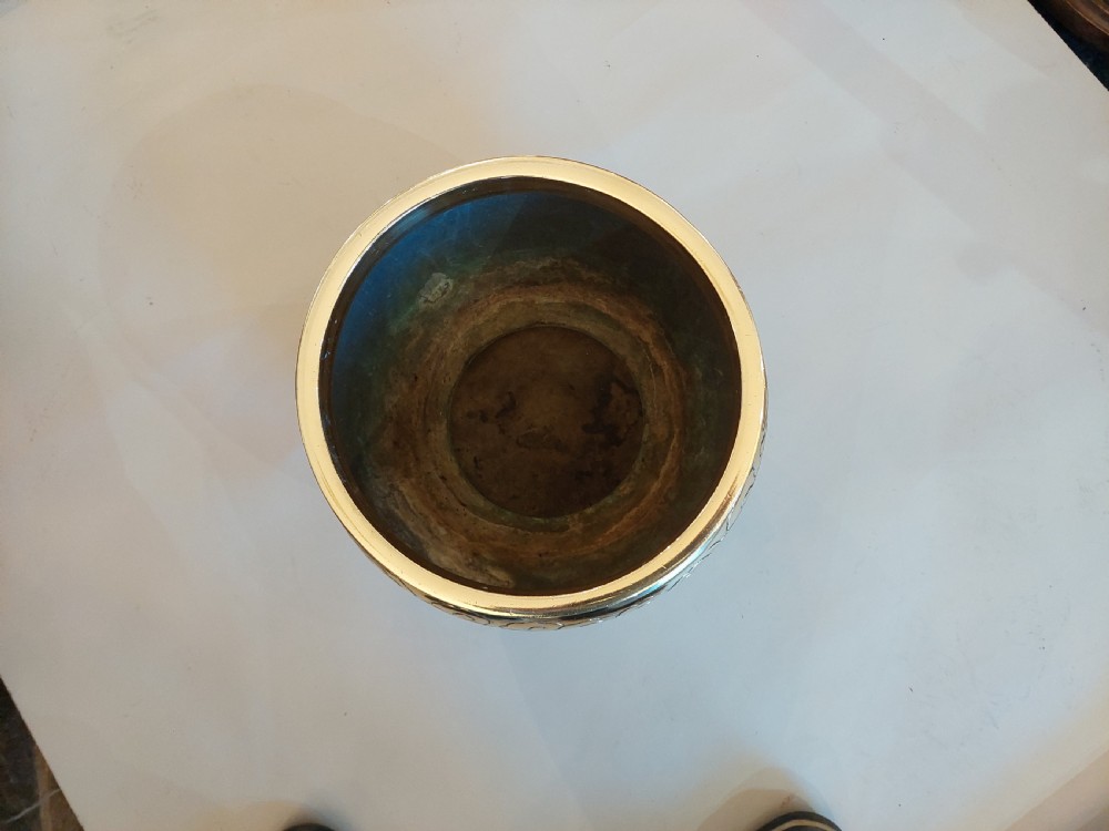 A rounded polished brass Japanese jardiniere with hand-chased relief dragons and clouds, resting on a stepped base. View III