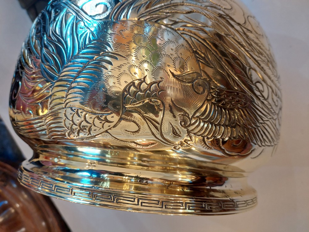 A rounded polished brass Japanese jardiniere with hand-chased relief dragons and clouds, resting on a stepped base. View V