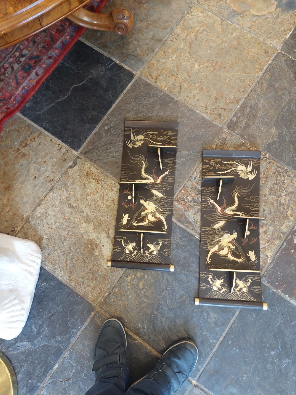 A pair of black lacquered wall shelves featuring scroll end caps and hand-painted gilt dragon and phoenix motifs with stepped display brackets. View II