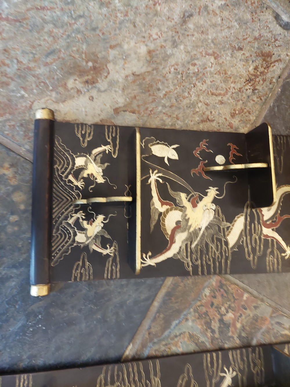 A pair of black lacquered wall shelves featuring scroll end caps and hand-painted gilt dragon and phoenix motifs with stepped display brackets. View VII