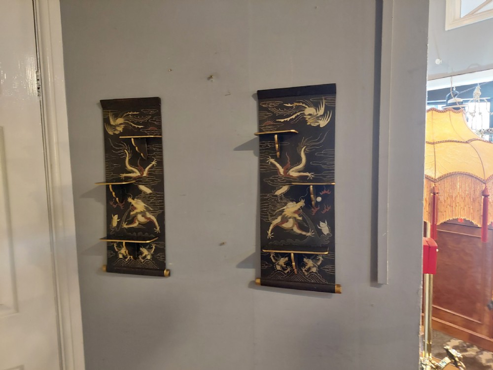 A pair of black lacquered wall shelves featuring scroll end caps and hand-painted gilt dragon and phoenix motifs with stepped display brackets. View IX