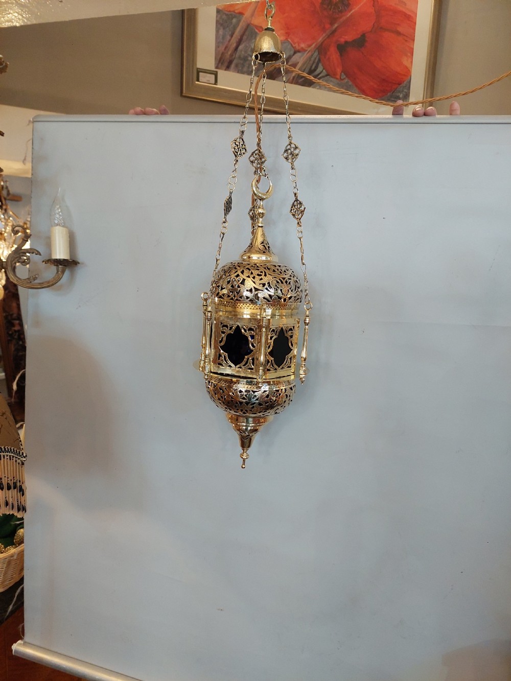 A hanging polished brass lantern featuring intricate pierced fretwork, dark glass insert panels, and three suspension chains topped with a crescent moon motif. View II