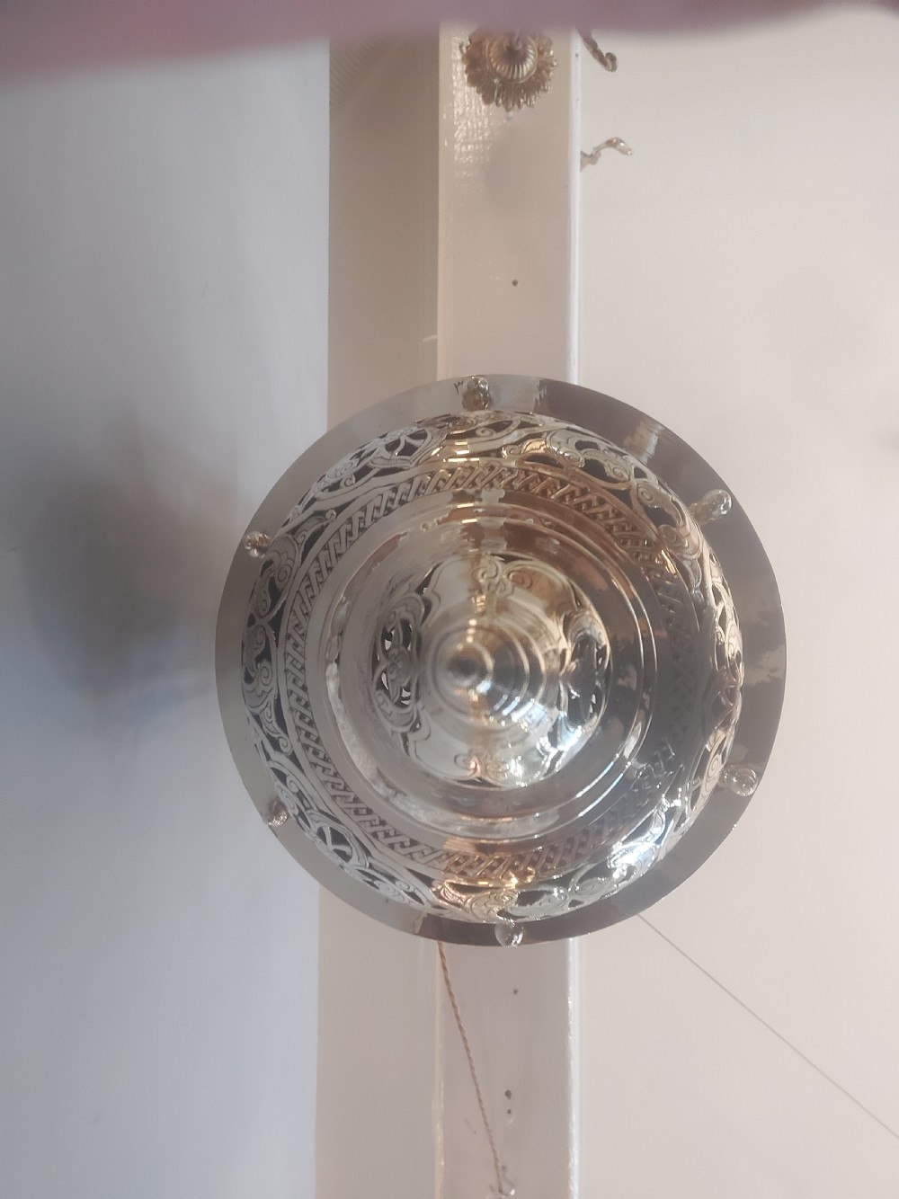 A hanging polished brass lantern featuring intricate pierced fretwork, dark glass insert panels, and three suspension chains topped with a crescent moon motif. View III