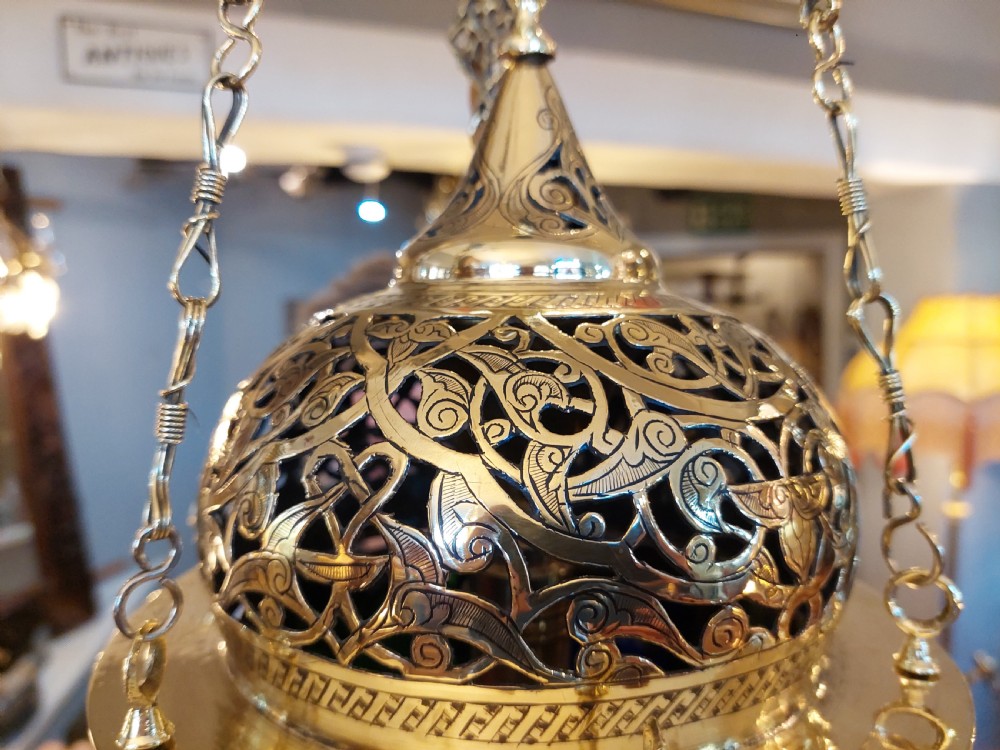 A hanging polished brass lantern featuring intricate pierced fretwork, dark glass insert panels, and three suspension chains topped with a crescent moon motif. View V