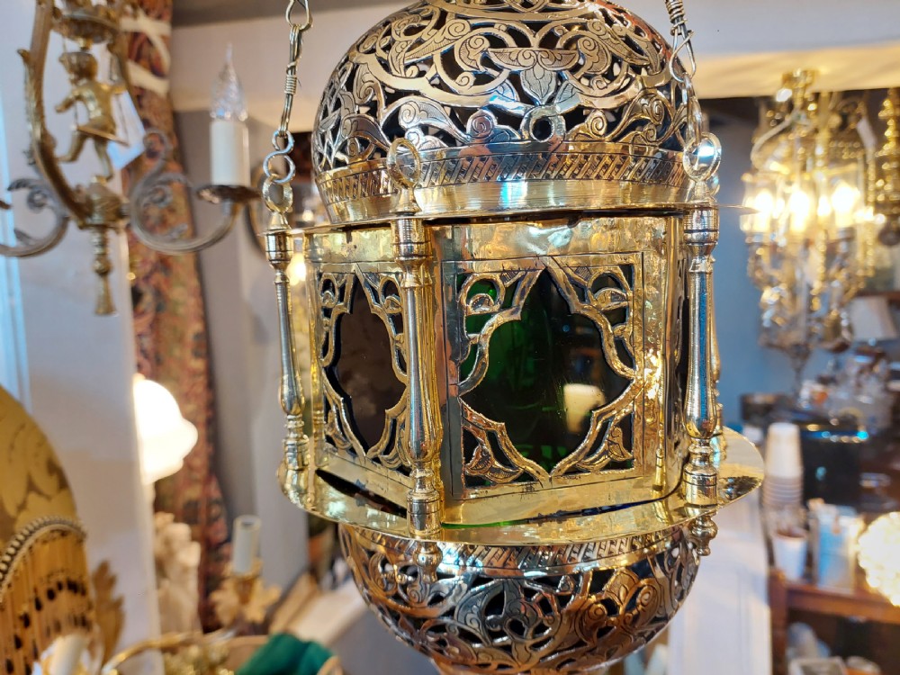 A hanging polished brass lantern featuring intricate pierced fretwork, dark glass insert panels, and three suspension chains topped with a crescent moon motif. View VII