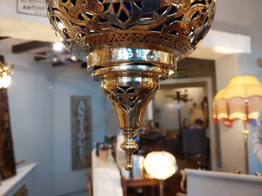A hanging polished brass lantern featuring intricate pierced fretwork, dark glass insert panels, and three suspension chains topped with a crescent moon motif. View VIII