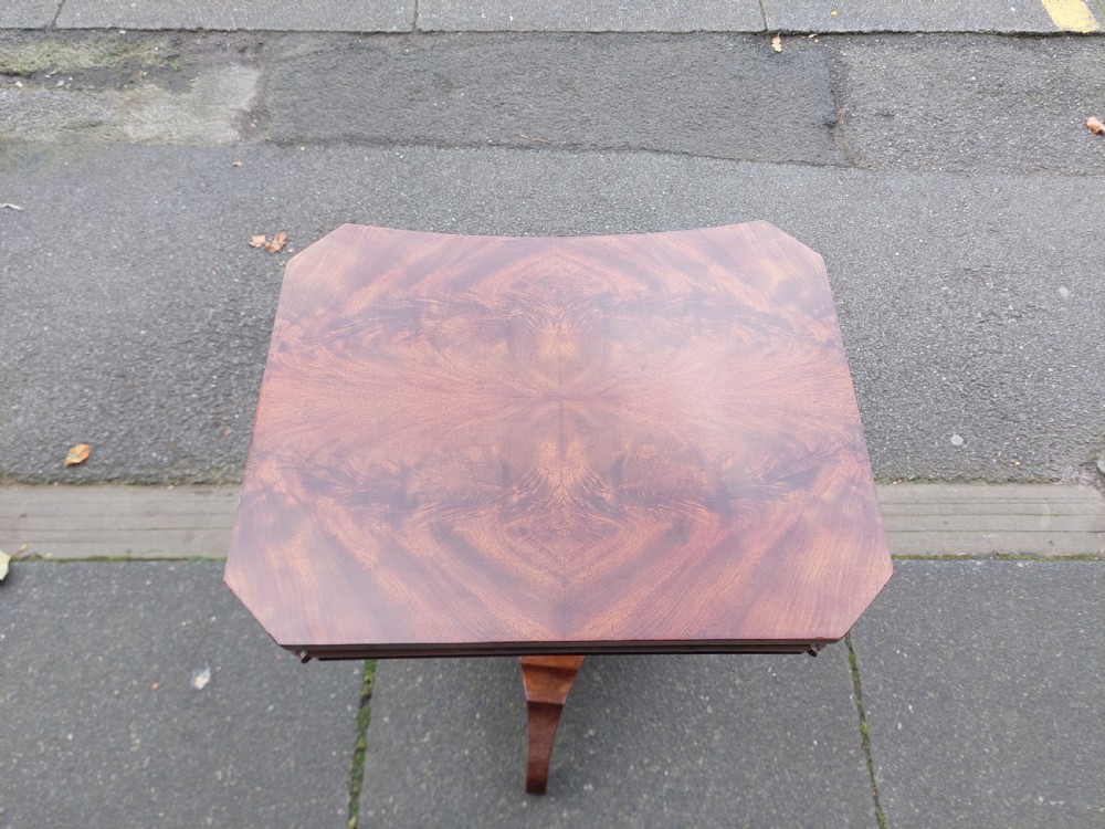 A flame mahogany Victorian sewing table featuring a canted corner top, a faceted turned pedestal column, and a scroll-cut tripod base. View V