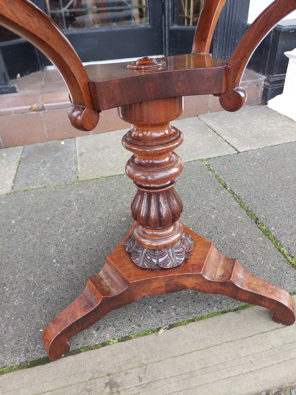A flame mahogany Victorian sewing table featuring a canted corner top, a faceted turned pedestal column, and a scroll-cut tripod base. View VII