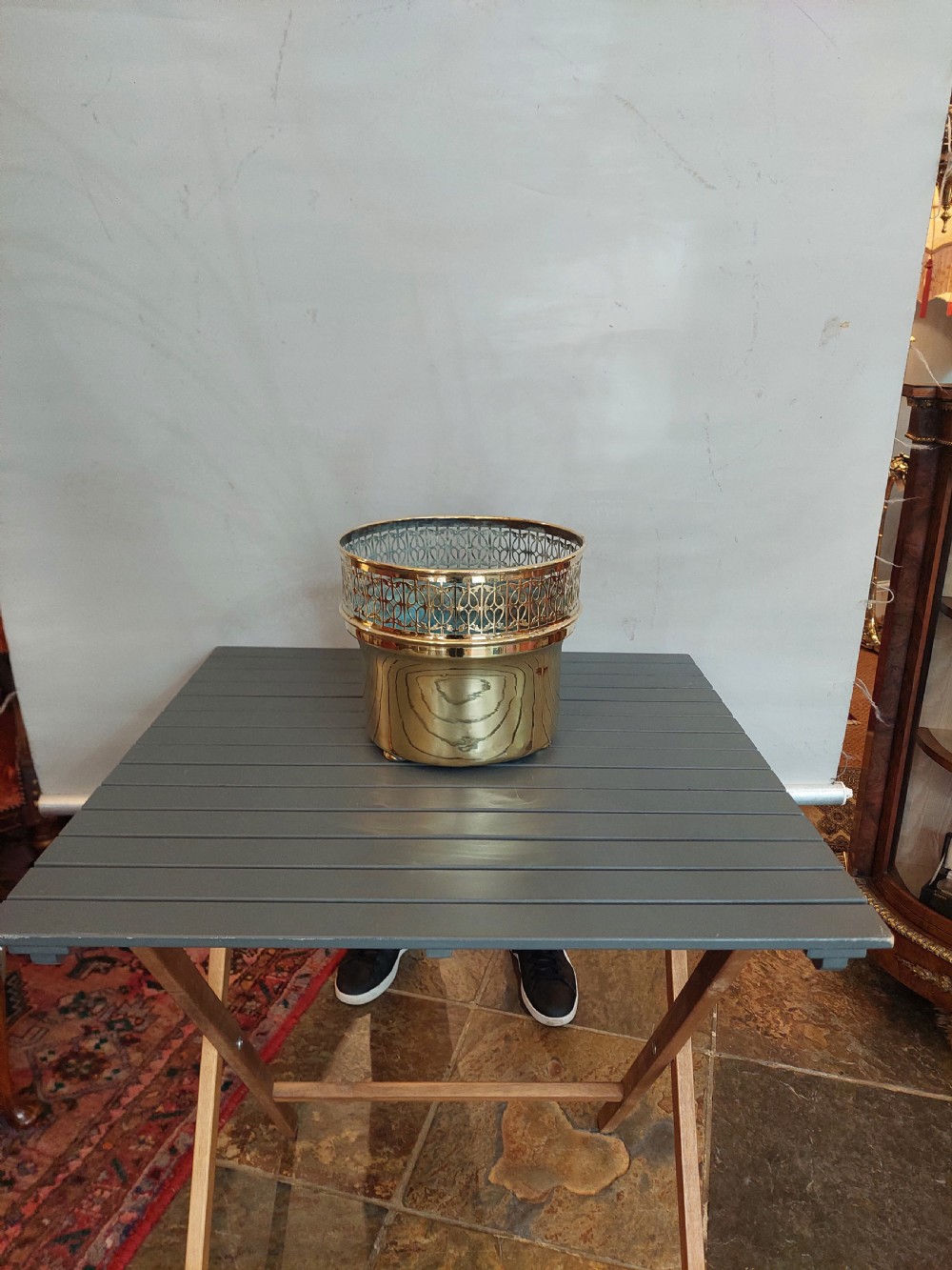 A cylindrical polished brass planter featuring a decorative pierced fretwork border near the upper rim and raised on small feet. View II