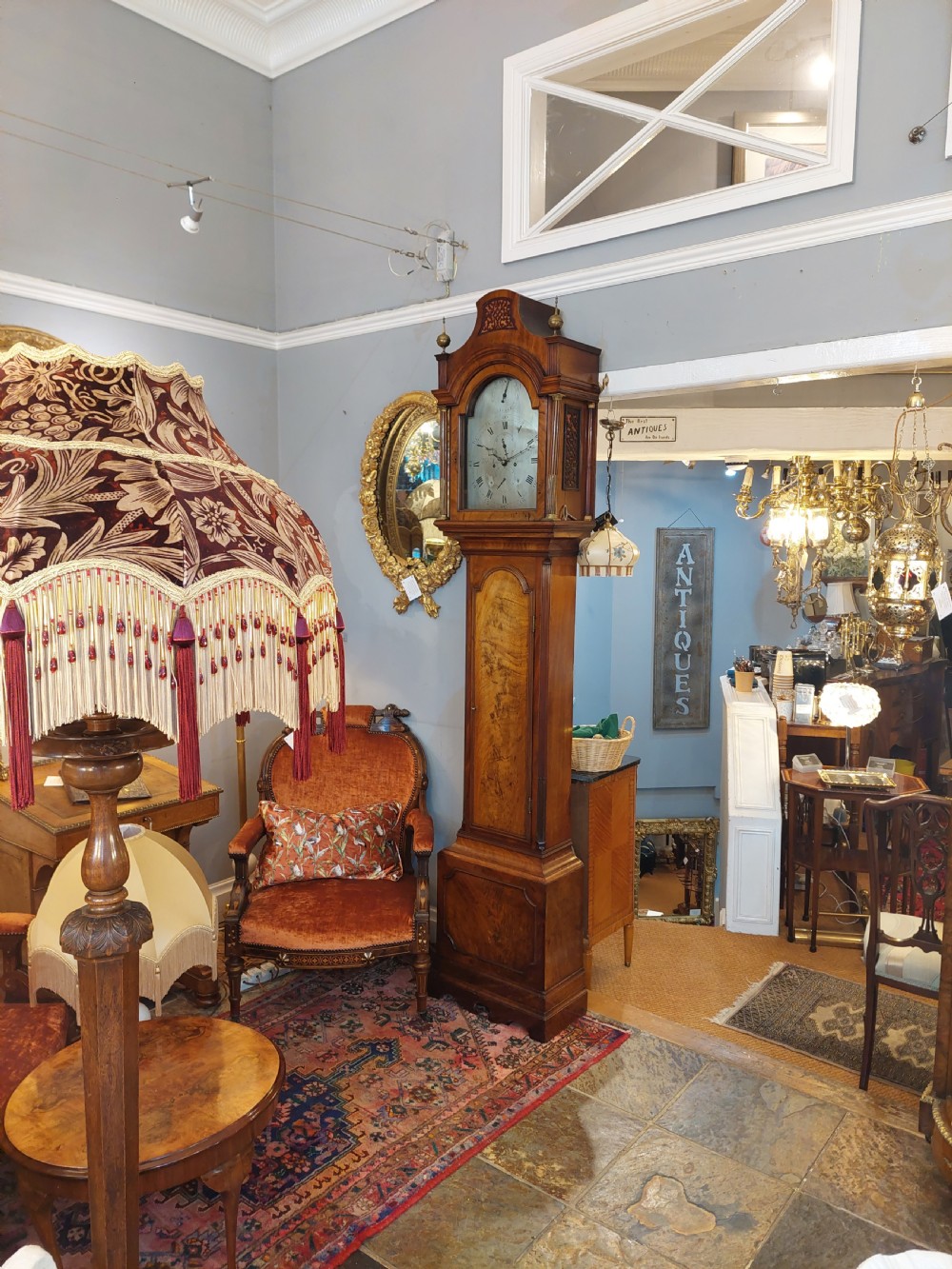 An 18th-century Georgian mahogany longcase clock featuring a pedimented hood with brass finials, an arched dial, and a flame mahogany trunk door. View IV