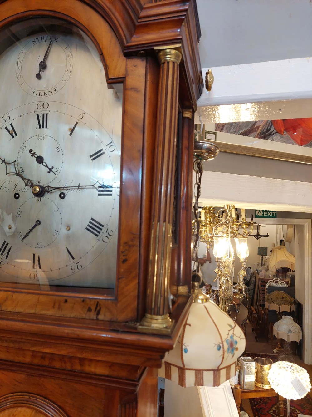 An 18th-century Georgian mahogany longcase clock featuring a pedimented hood with brass finials, an arched dial, and a flame mahogany trunk door. View VIII