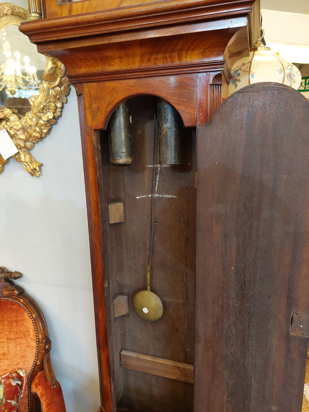 An 18th-century Georgian mahogany longcase clock featuring a pedimented hood with brass finials, an arched dial, and a flame mahogany trunk door. View XII