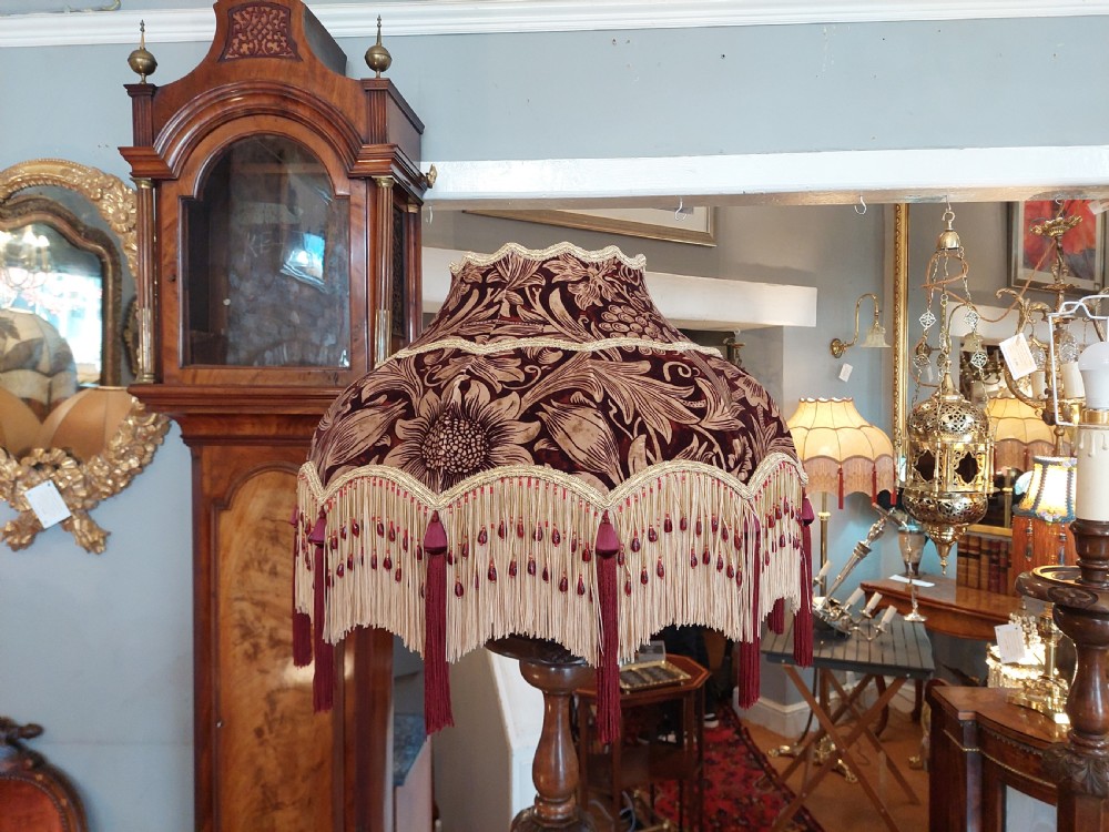 A matched pair of turned dark oak standard lamps featuring ornate burgundy and cream patterned fabric shades with tassel fringe. View IX
