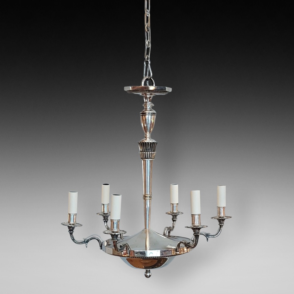 An early twentieth-century silver-plated six-arm ceiling chandelier featuring candle-style light sockets and a central fluted column.