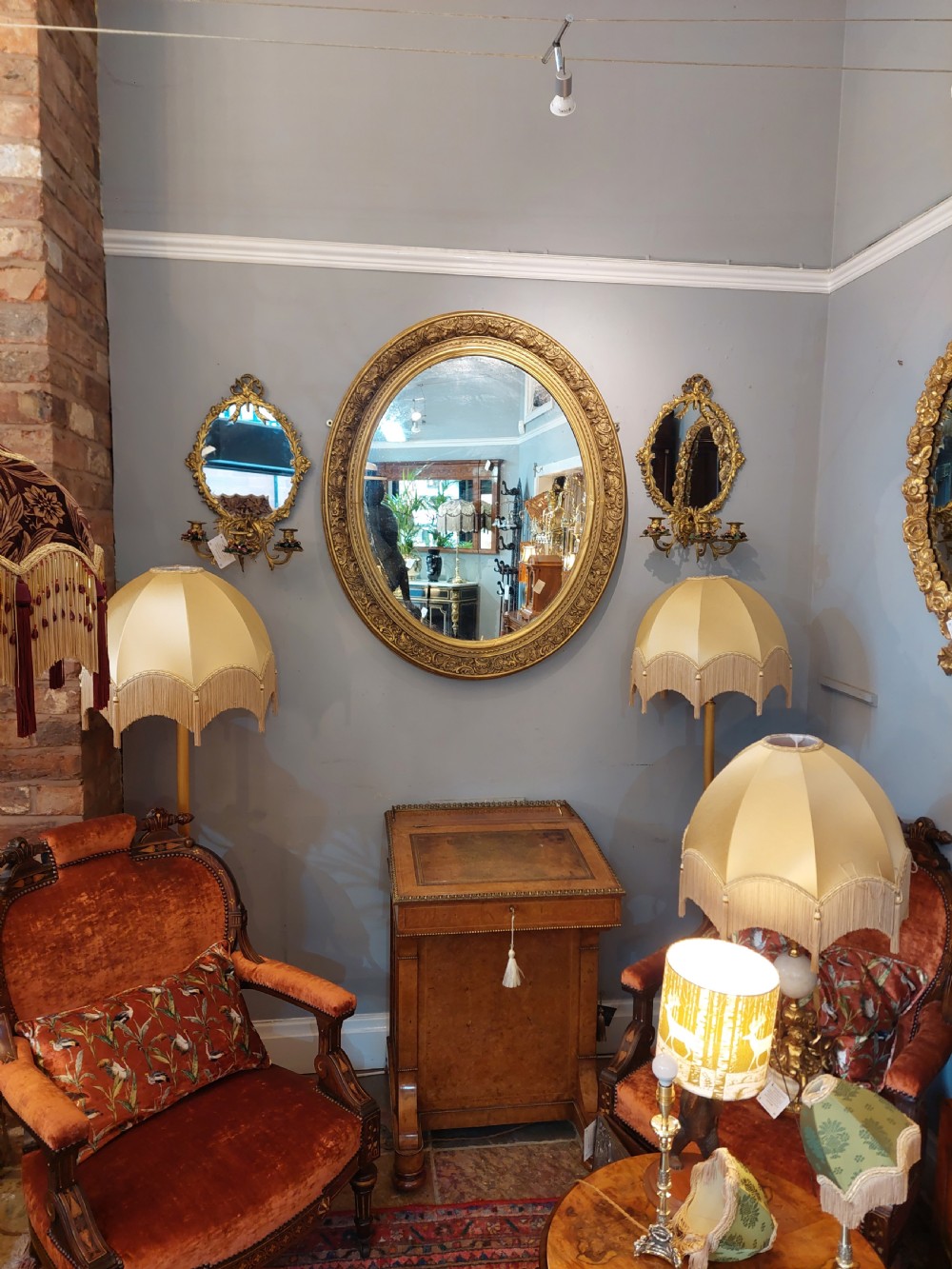 A nineteenth-century oval wall mirror featuring a heavily carved giltwood frame with floral and scrolling moulding details. View X