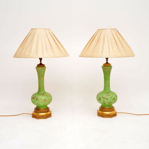 fig 1. A pair of antique green glass table lamps decorated with gilt floral motifs, raised on ornate gold bases with pleated cream shades.