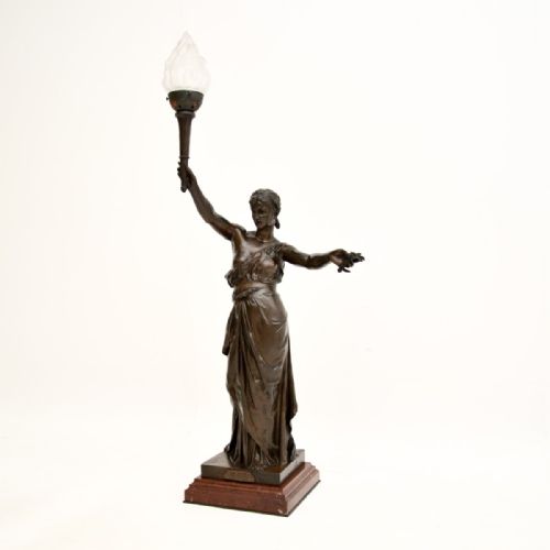 fig 1. A dark patinated French bronze classical female figure holding aloft a torch light fixture with a flame glass shade, set on a red marble base.