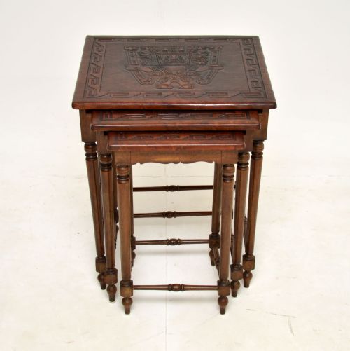fig 1. A set of three dark wood nesting side tables featuring turned legs, horizontal stretchers, and embossed leather tops decorated with geometric motifs.