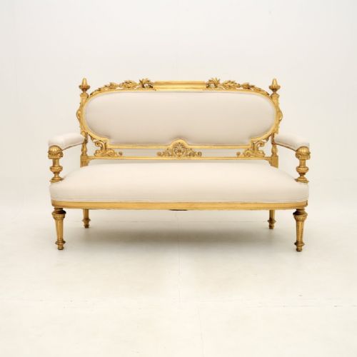 fig 1. A Swedish Empire giltwood settee featuring a carved leaf crest, finials, fluted legs, and neutral cream upholstery.