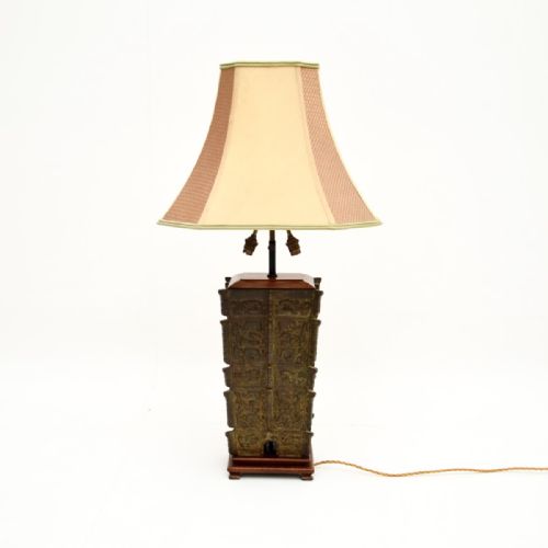 fig 1. A large patinated bronze table lamp inspired by archaic oriental vessels, mounted on a dark wooden base with a cream fabric lampshade.