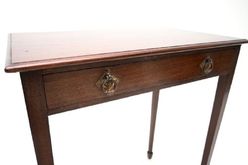 fig 1. An Edwardian mahogany side table featuring a single drawer with twin brass handles and slender tapered legs ending in spade feet.