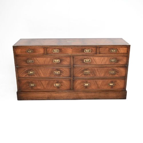 fig 1. A wide mahogany military campaign style chest of drawers featuring flush recessed brass handles, protective brass corner mounts, and a rich wood grain finish.