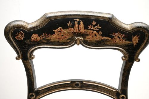 fig 1. A pair of Victorian black lacquered side chairs featuring gilt Chinoiserie landscape painting on the backrests, turned front legs, and cream upholstered seats.