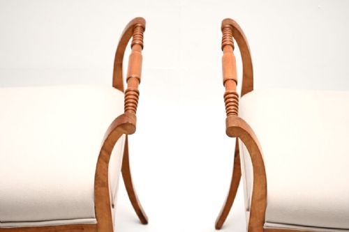 fig 1. A pair of antique Swedish Biedermeier stools crafted from golden satin birch with swept legs, turned arm handles, and cream upholstered seats.