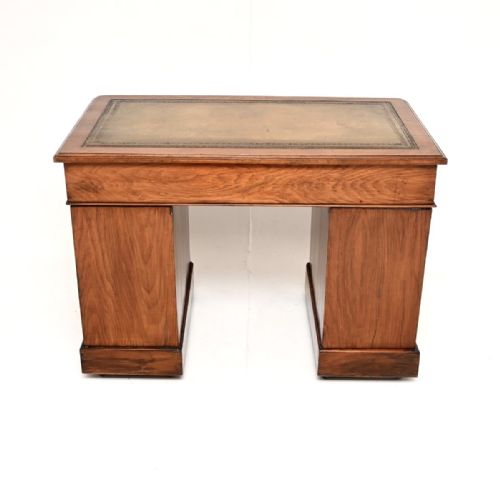 fig 1. A Victorian walnut pedestal desk featuring nine drawers with turned wooden knobs and a green gilt-tooled leather writing surface.