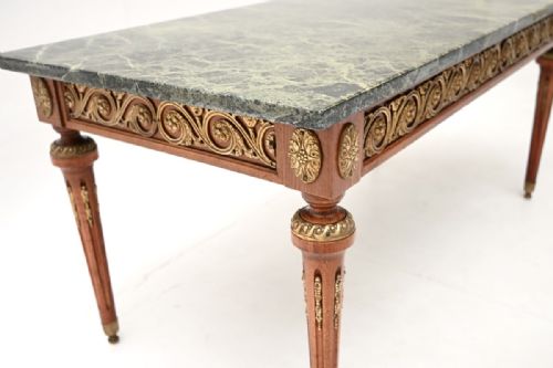 fig 1. A rectangular French Neoclassical coffee table featuring a dark green veined marble top, ornate gilt bronze frieze detailing, and fluted tapered legs.