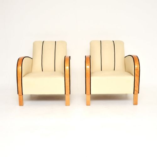 fig 1. A pair of Swedish Art Deco armchairs upholstered in cream leather featuring curved satin birch armrests and black piping.