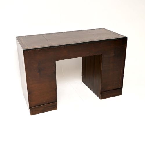 fig 1. An Art Deco dark brown figured walnut pedestal desk featuring a leather insert top, nine drawers with dark linear handles, and keyhole escutcheons.