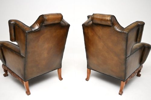 fig 1. A pair of antique brown leather wingback armchairs with carved wooden aprons and cabriole legs.