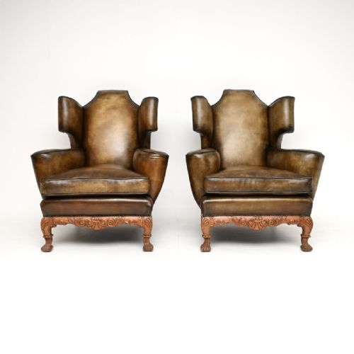 fig 2. A pair of antique brown leather wingback armchairs with carved wooden aprons and cabriole legs.