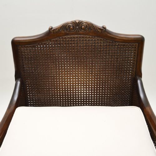 fig 1. A pair of antique Swedish satin birch bergere armchairs featuring carved wood frames with claw and ball feet, caned side panels, and cream upholstered cushions.