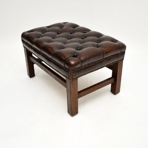 fig 1. A deep-buttoned dark brown leather footstool with brass stud detailing and dark mahogany legs.
