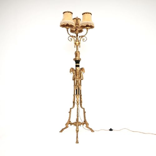 fig 1. A French gilt bronze three-light floor lamp with fabric shades, ram head embellishments, and a tripod base.
