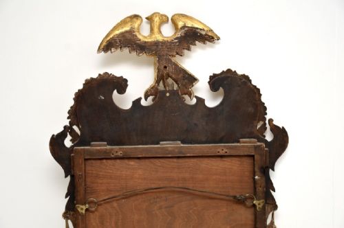 fig 1. A Georgian period mahogany parcel gilt wall mirror featuring a carved golden eagle crest and side foliage garlands.