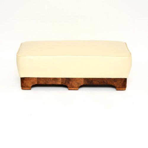 fig 1. An Art Deco low rectangular stool featuring a cream leather upholstered cushioned top set above a burr walnut plinth base with shaped feet.