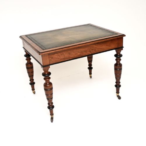 fig 1. A Victorian mahogany writing desk featuring a leather inset top, two frieze drawers with wooden knob handles, and turned legs ending in brass castors.