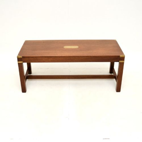 fig 1. A rectangular mahogany campaign style coffee table featuring protective brass corner brackets and a central brass inset plaque, supported by straight legs with a lower stretcher.