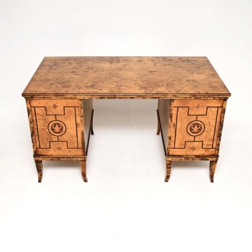 fig 2. An antique Swedish Biedermeier style pedestal desk crafted from figured satin birch with dark wood geometric inlays and tapered legs.