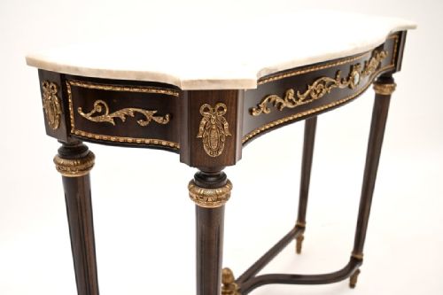 fig 1. A French Louis XVI style walnut console table featuring a contoured white marble top, tapered fluted legs, gilt-bronze mounts, and a central porcelain plaque.