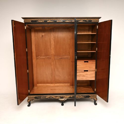 fig 1. A large black lacquered three-door wardrobe decorated with detailed gold chinoiserie landscapes and supported by cabriole feet.
