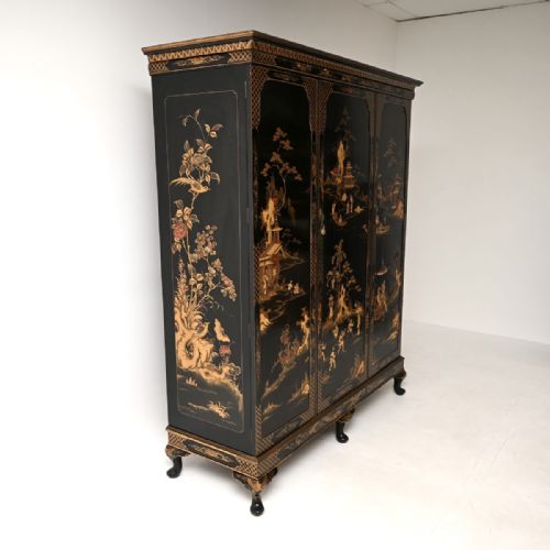 fig 2. A large black lacquered three-door wardrobe decorated with detailed gold chinoiserie landscapes and supported by cabriole feet.