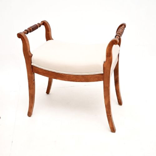 fig 1. A pair of Swedish satin birch Biedermeier stools featuring curved cream upholstered seats, turned handle grips, and sweeping splayed legs.