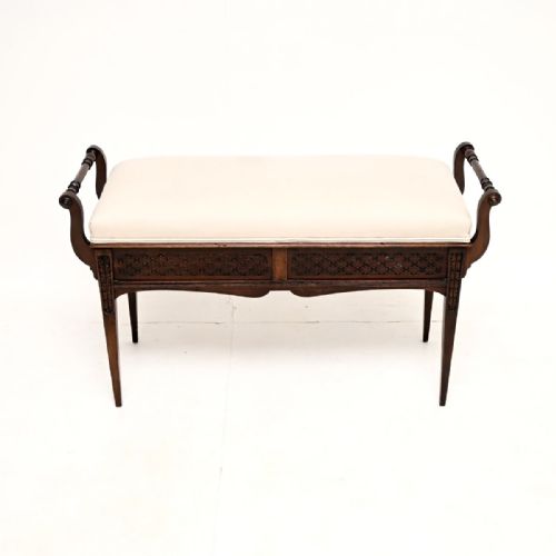 fig 1. Victorian mahogany duet piano stool featuring cream upholstered seat, turned side handles, pierced fretwork frieze, and square tapered legs.